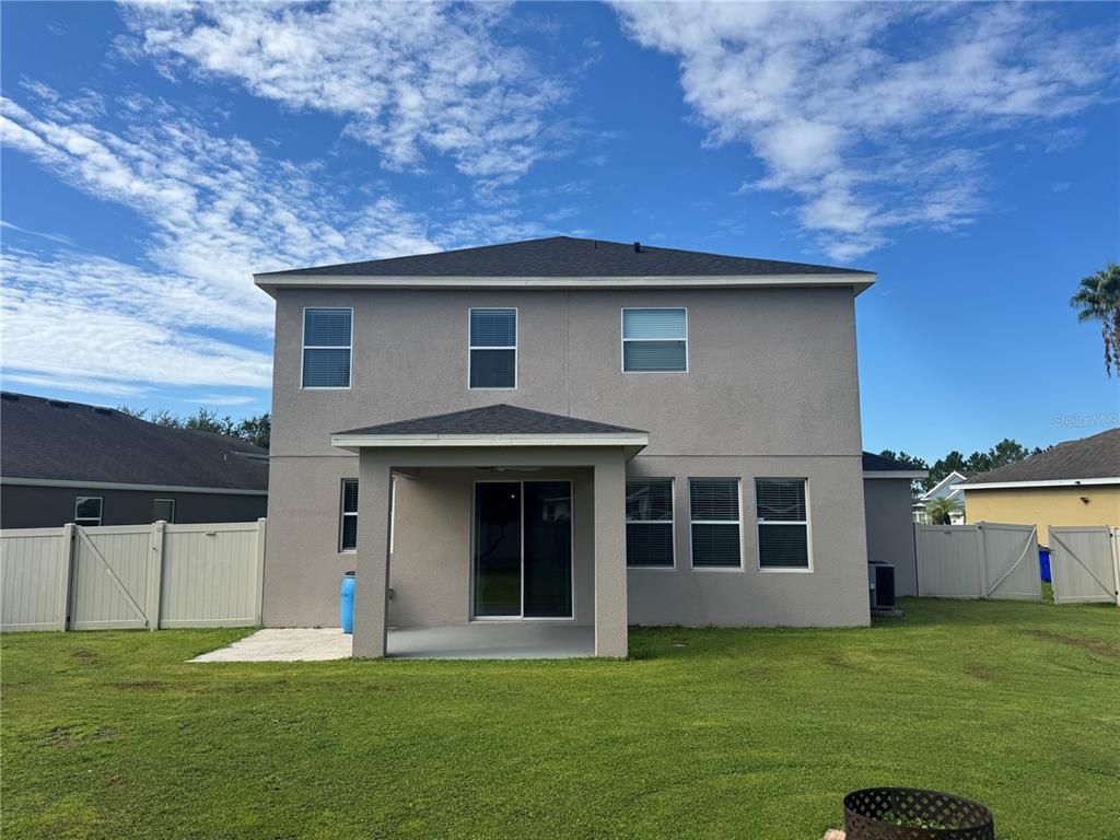 The rear exterior of a two-story house features a covered patio and a fenced yard — 3504 BLITHE COURT, ST CLOUD, FL