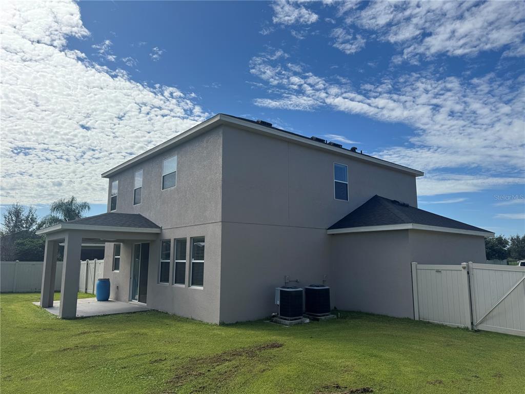 The rear exterior of a two-story house features a covered patio and two air conditioning units — 3504 BLITHE COURT, ST CLOUD, FL