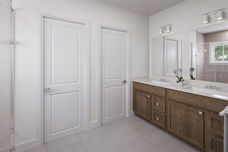 A bathroom features a double-sink wooden vanity, white doors, and light-colored tile flooring — 847 WENDY ROSE WAY, LEESBURG, FL