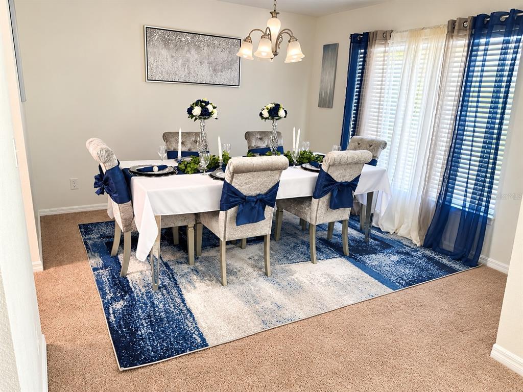 A dining room features a table with blue-accented chairs, a patterned rug, and window curtains — 24107 MILFORD DRIVE, EUSTIS, FL