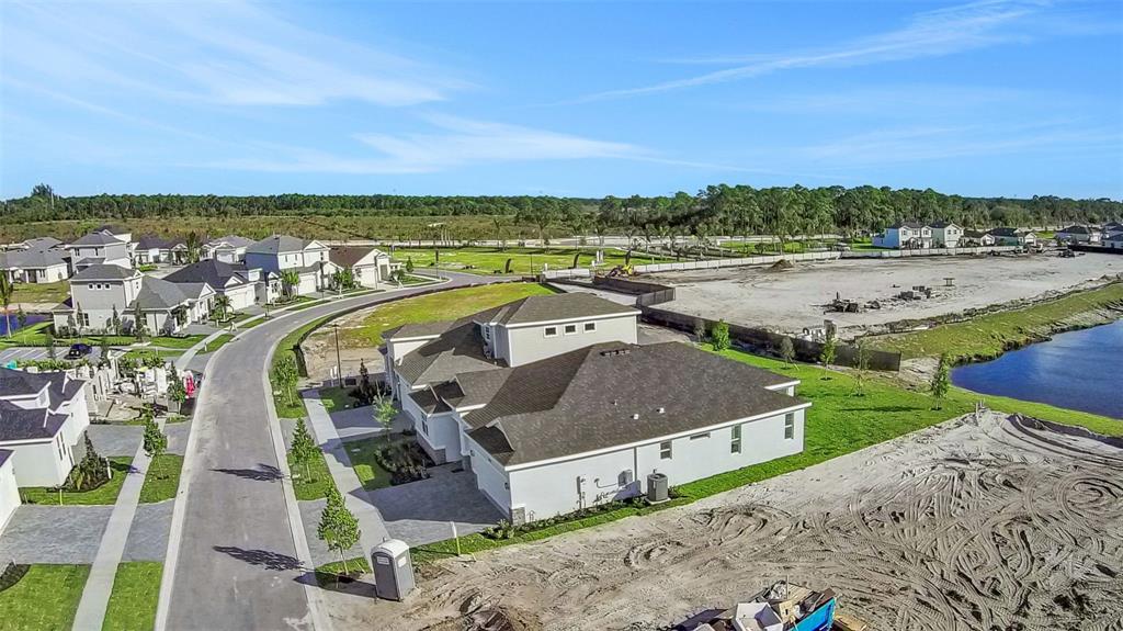 An aerial view shows a suburban house with a dark roof near a construction site — 5420 NW CAMBERLY COURT, PORT ST LUCIE, FL