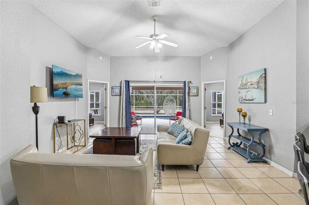A living room features a vaulted ceiling, tile floors, two sofas, and sliding glass doors — 536 PINE CONE DRIVE, DAVENPORT, FL