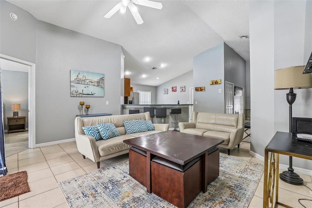A living room features light-colored leather sofas, a central coffee table, and tile flooring — 536 PINE CONE DRIVE, DAVENPORT, FL