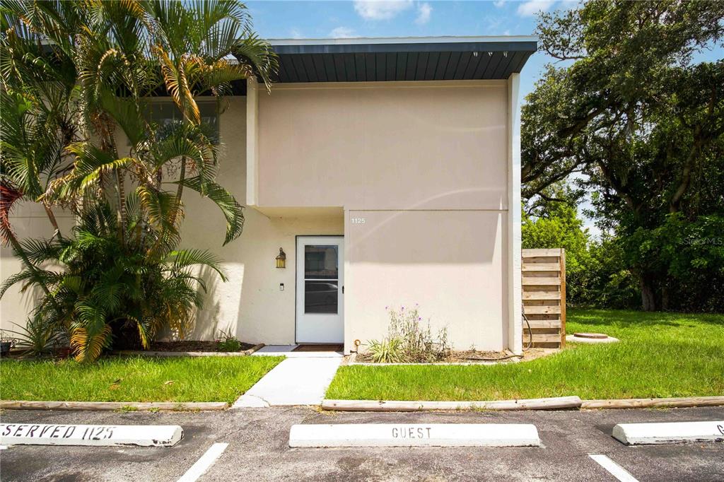 The exterior of a two-story residential building features a white front door and parking spaces — 1125 LONGFELLOW WAY UNIT 125-B, SARASOTA, FL