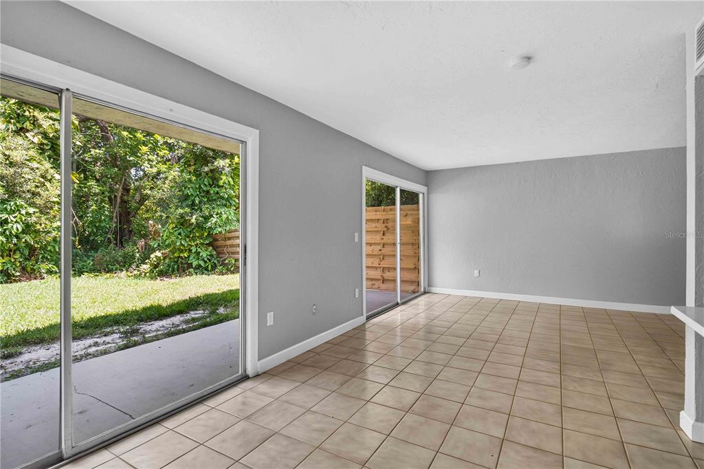 An empty room with light-colored tile flooring, gray walls, and two sliding glass doors — 1125 LONGFELLOW WAY UNIT 125-B, SARASOTA, FL