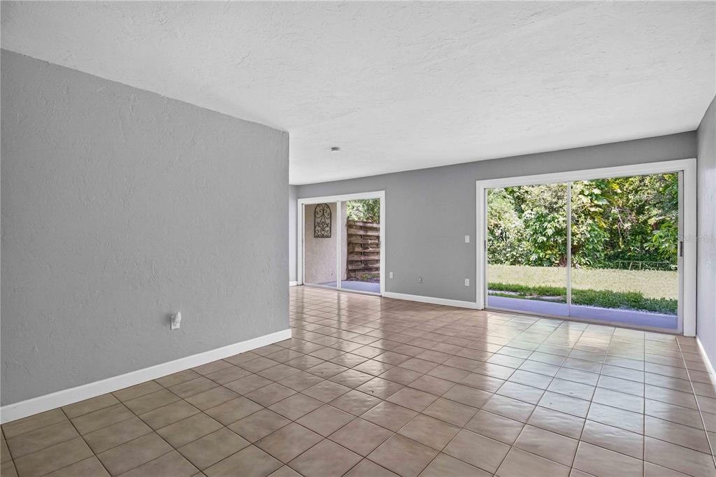 A living room with gray walls, tile flooring, and two sliding glass doors leading outside — 1125 LONGFELLOW WAY UNIT 125-B, SARASOTA, FL