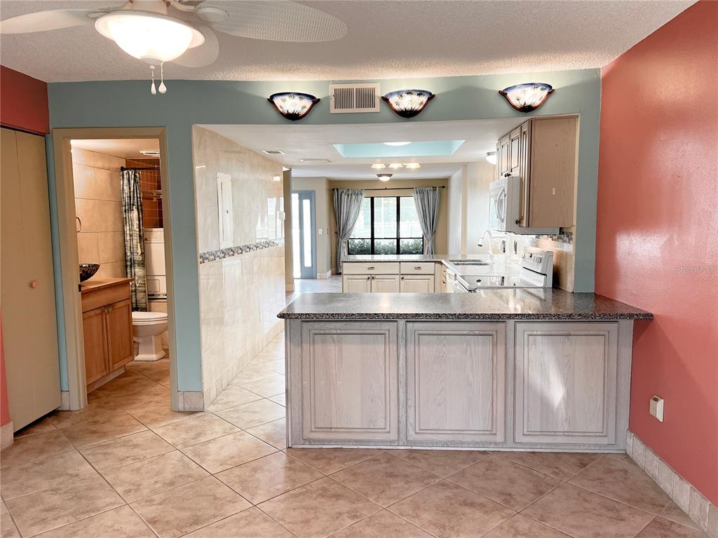 A kitchen with a breakfast bar, light-colored cabinets, and tile flooring opens to a bathroom — 1849 ABRICO DRIVE UNIT K9, LUTZ, FL
