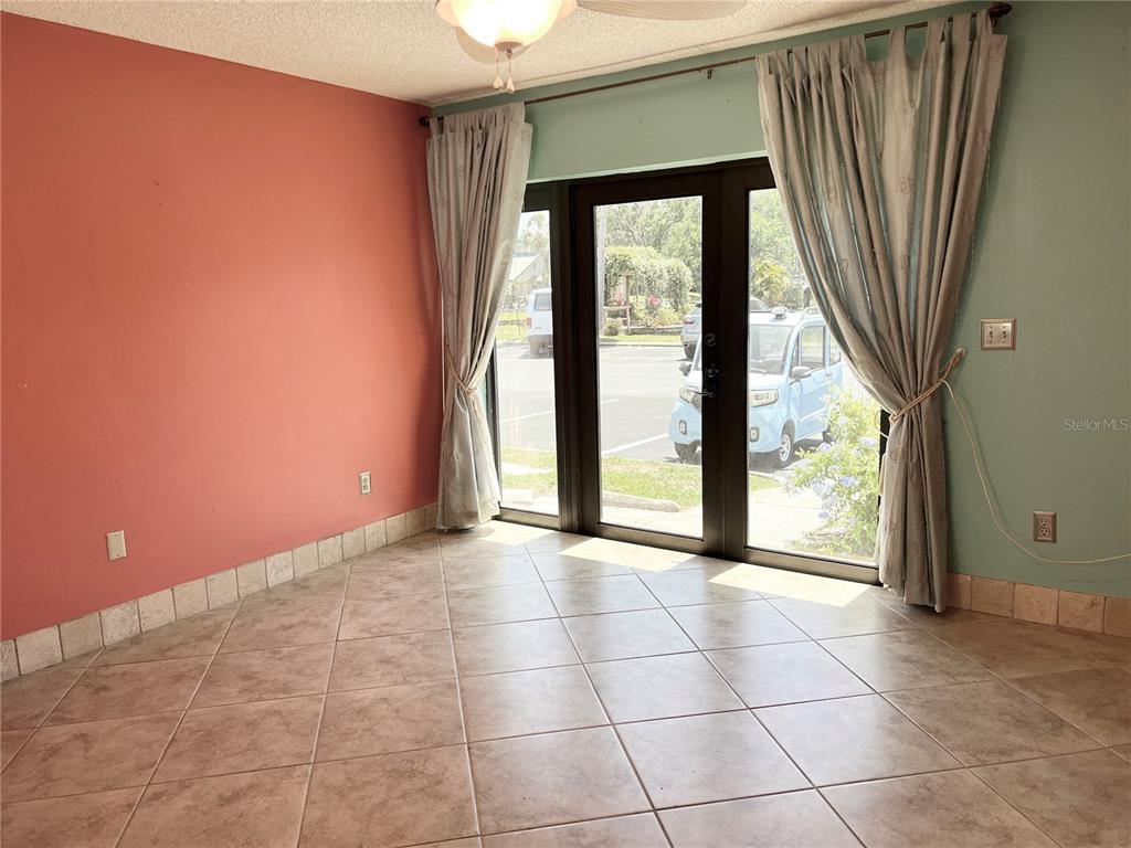 A room with tiled floors, a coral wall, and glass doors looking out onto a parking lot — 1849 ABRICO DRIVE UNIT K9, LUTZ, FL