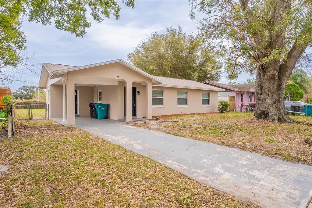 A single-story house with a beige exterior, a concrete driveway, and a covered carport — 1335 LESCOT LANE, ORLANDO, FL
