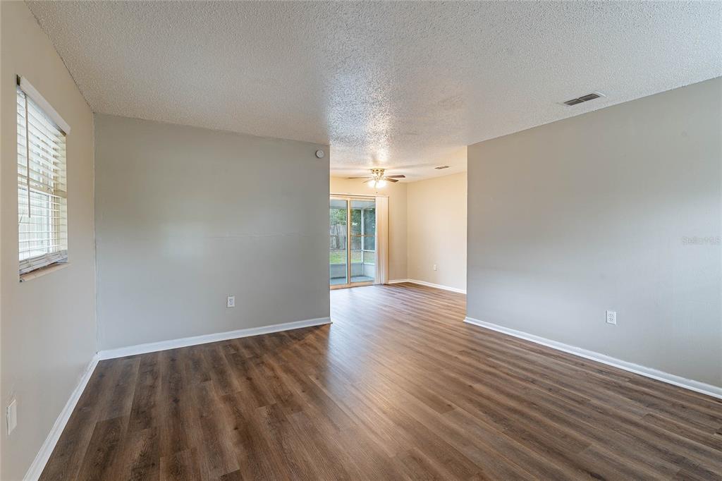 An empty room with light gray walls, wood-look flooring, and a sliding glass door — 1335 LESCOT LANE, ORLANDO, FL