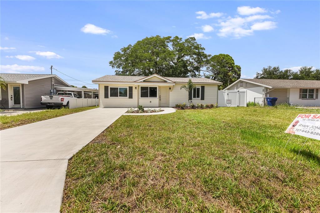 A single-story house with light-colored siding and a concrete driveway sits on a grassy lot — 7851 40TH AVE N, ST PETERSBURG, FL