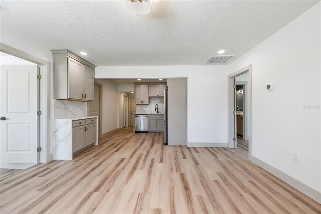 A kitchen and dining area with light wood-look flooring, gray cabinets, and white countertops — 7851 40TH AVE N, ST PETERSBURG, FL