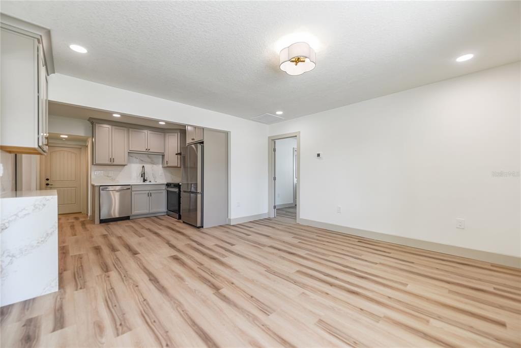 A kitchen with grey cabinets and stainless steel appliances opens into a spacious living area — 7851 40TH AVE N, ST PETERSBURG, FL