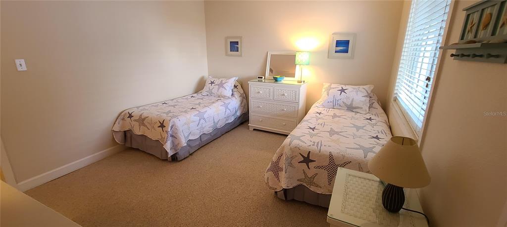 A bedroom features two twin beds with starfish-patterned quilts, a white dresser, and carpeted flooring — 815 OCEAN SHORE BOULEVARD UNIT 12A, ORMOND BEACH, FL