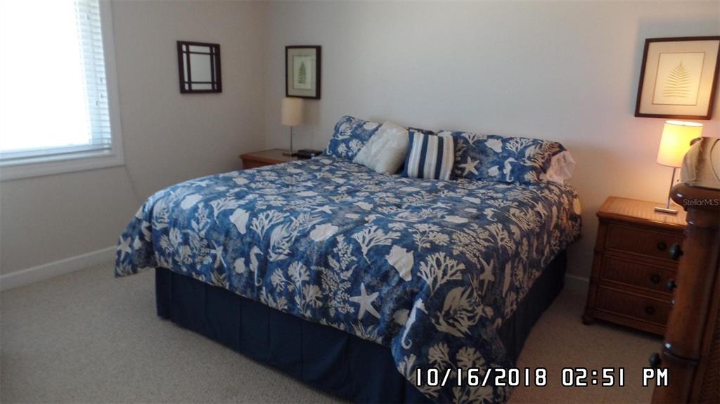A bedroom features a bed with a blue and white coastal-patterned comforter and two nightstands — 815 OCEAN SHORE BOULEVARD UNIT 12A, ORMOND BEACH, FL