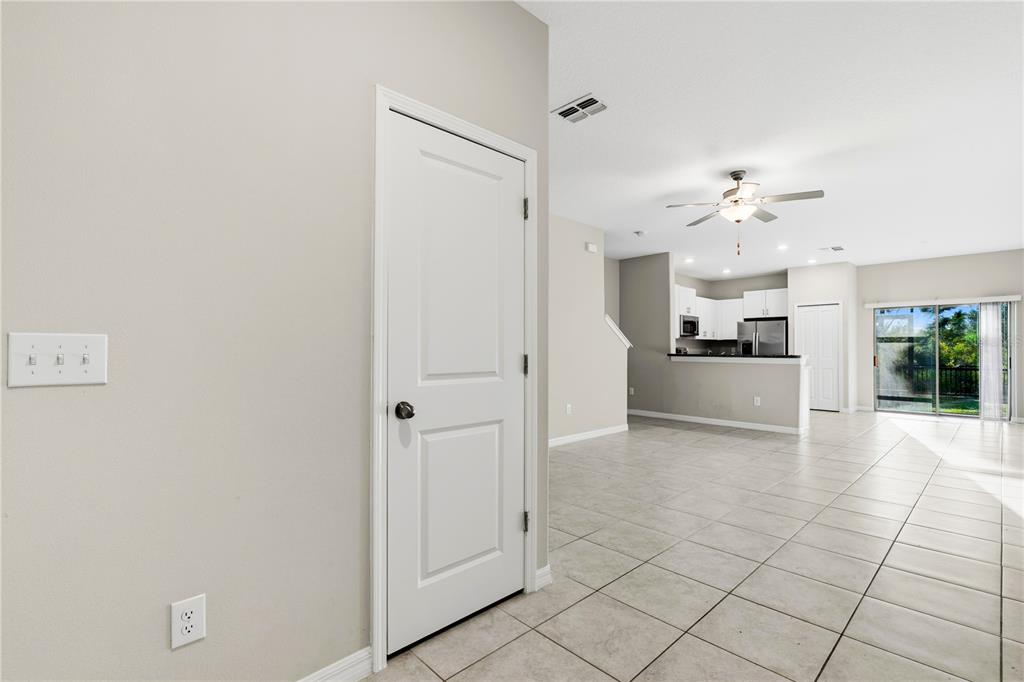 A tiled entryway leads to an open-concept kitchen and living area with a sliding glass door — 3527 BELLMEADE COURT, WESLEY CHAPEL, FL