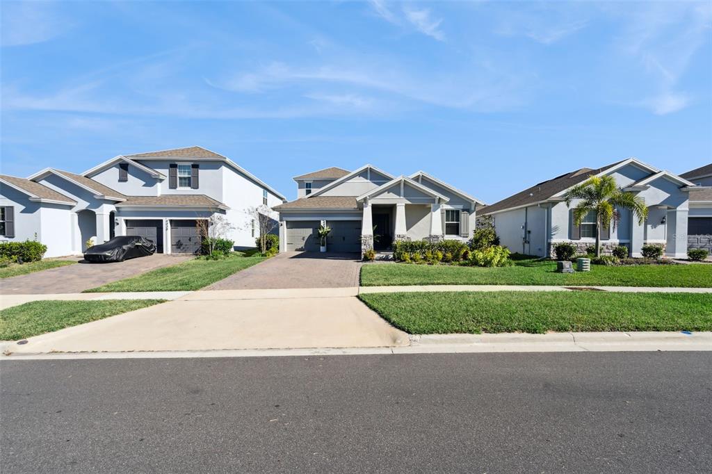 A street view of three suburban single-family homes with driveways and manicured lawns — 4442 LIONS GATE DRIVE, CLERMONT, FL