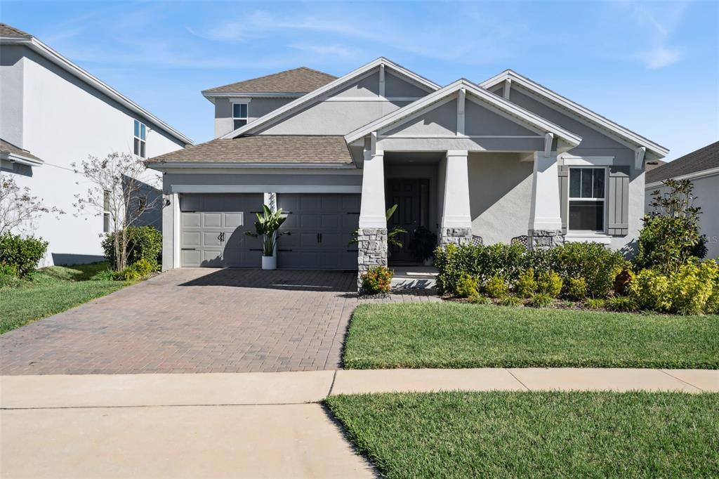 A two-story suburban house with a gray stucco exterior, stone accents, and a paved driveway — 4442 LIONS GATE DRIVE, CLERMONT, FL