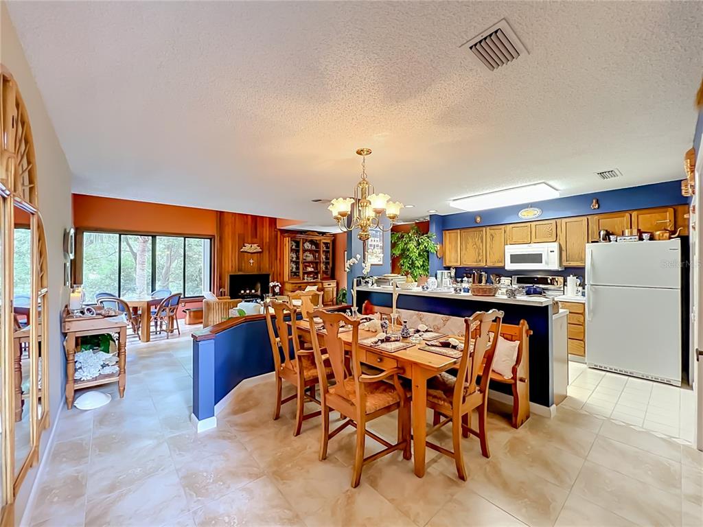 A dining area with a wooden table and chairs sits before an open-concept kitchen — 2184 WOODBRIDGE ROAD UNIT 2184, LONGWOOD, FL