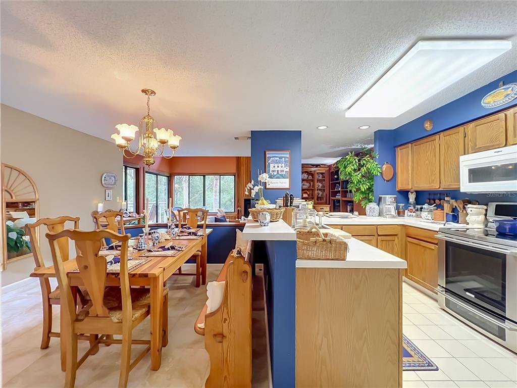 A dining area with a wooden table and chairs sits adjacent to a blue-walled kitchen — 2184 WOODBRIDGE ROAD UNIT 2184, LONGWOOD, FL