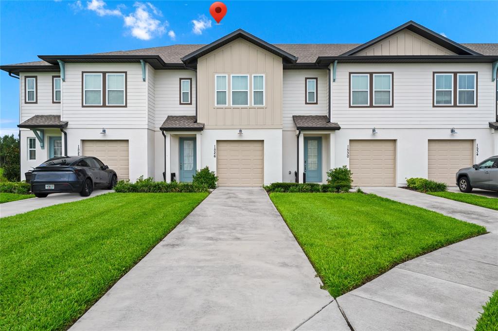 A row of two-story townhomes with beige garages, light blue doors, and white siding — 1526 DISCOVERY STREET, DAVENPORT, FL