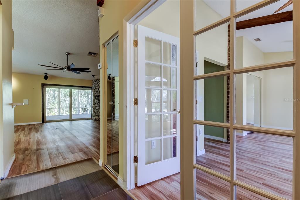 A hallway with wood-look flooring leads to a living area with a stone fireplace — 1795 BAYHILL DRIVE, OLDSMAR, FL