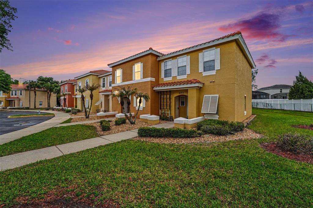 A two-story yellow stucco townhouse with a tile roof and a front walkway — 1081 PARK RIDGE CIRCLE, KISSIMMEE, FL