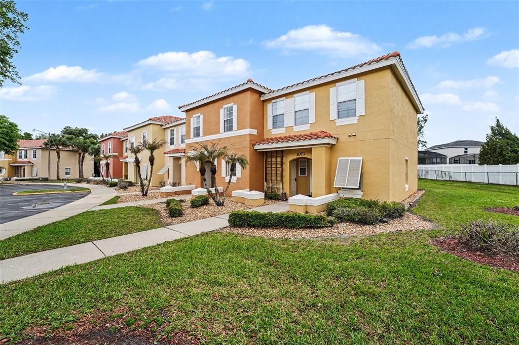 A two-story townhouse with a tan stucco exterior and a red tile roof — 1081 PARK RIDGE CIRCLE, KISSIMMEE, FL
