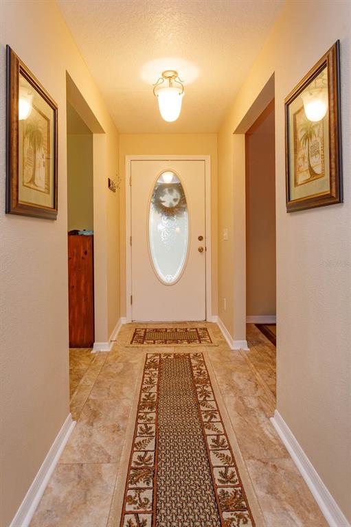 A tiled entryway features a white front door with an oval window and two framed pictures — 24353 CALUSA BOULEVARD, EUSTIS, FL