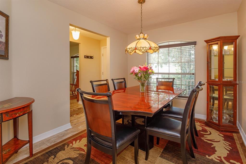 A dining room features a wooden table with chairs, a hanging lamp, and a display cabinet — 24353 CALUSA BOULEVARD, EUSTIS, FL