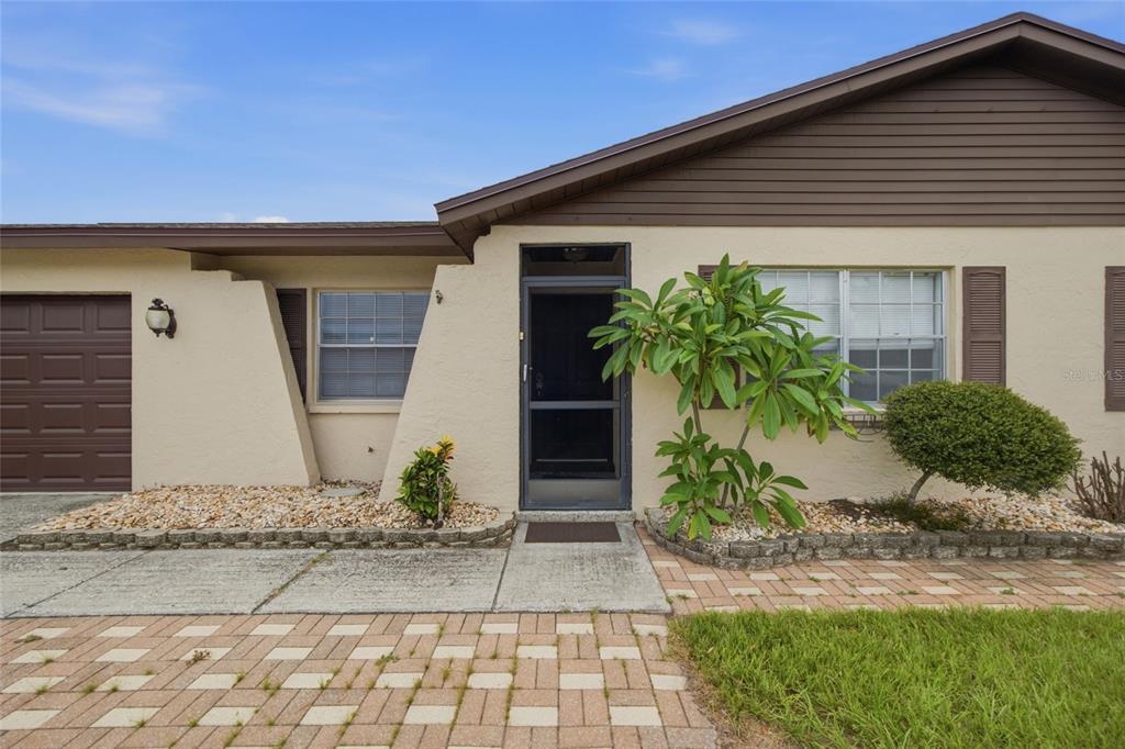 A single-story house exterior features a brown garage door, a front entrance, and landscaped beds — 2971 FOREST CIRCLE, SEFFNER, FL