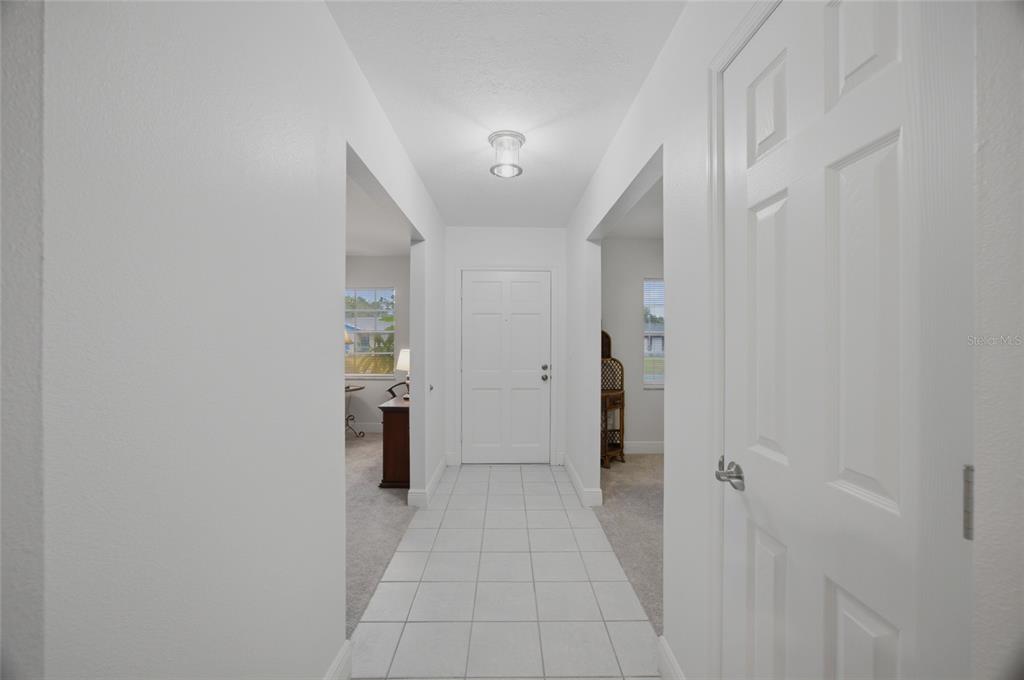 A white-tiled entryway leads to a front door flanked by two carpeted rooms — 2971 FOREST CIRCLE, SEFFNER, FL