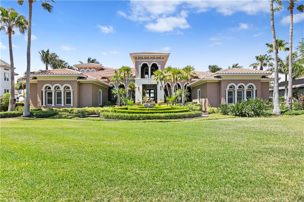 A large, single-story Mediterranean-style house features a tiled roof, arched windows, and a landscaped lawn — 6308 MARBELLA BOULEVARD, APOLLO BEACH, FL
