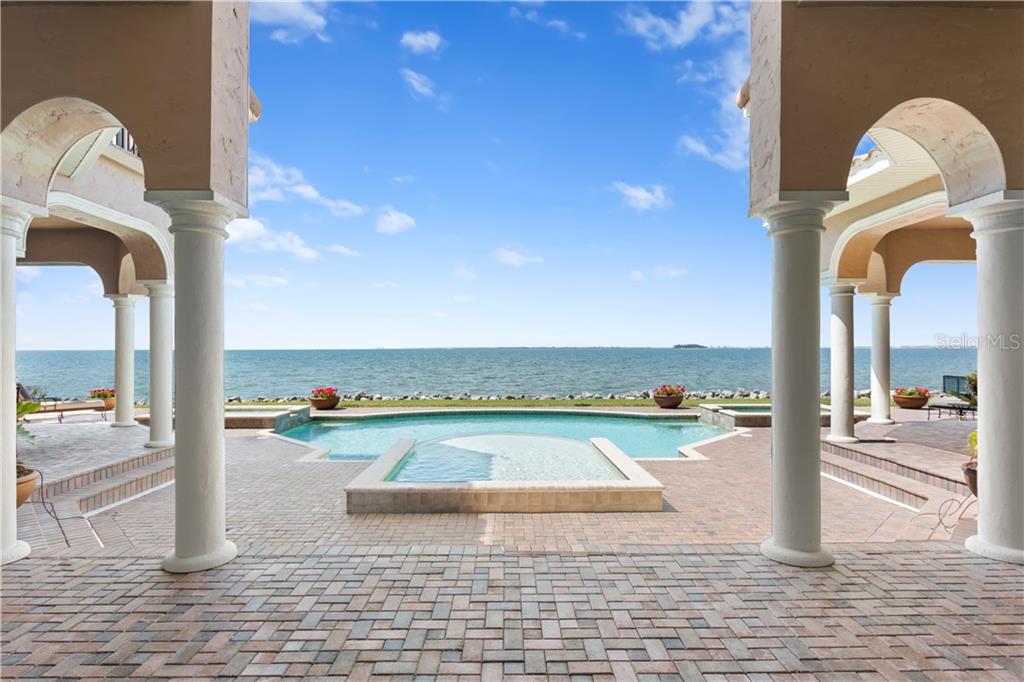 A paved patio with columns overlooks a swimming pool and the ocean — 6308 MARBELLA BOULEVARD, APOLLO BEACH, FL