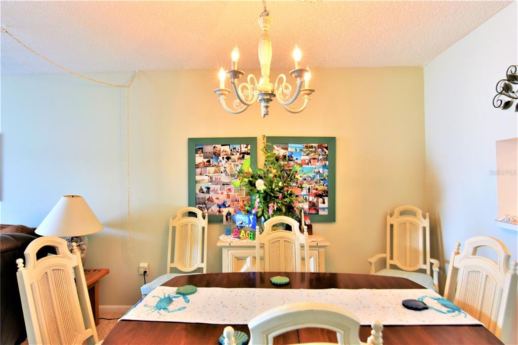 A dining room features a wooden table, white chairs, a chandelier, and two photo collages — 18304 GULF BOULEVARD UNIT 504, REDINGTON SHORES, FL