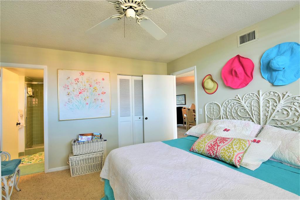 A bedroom features a white wicker headboard, colorful wall-mounted hats, and a ceiling fan — 18304 GULF BOULEVARD UNIT 504, REDINGTON SHORES, FL