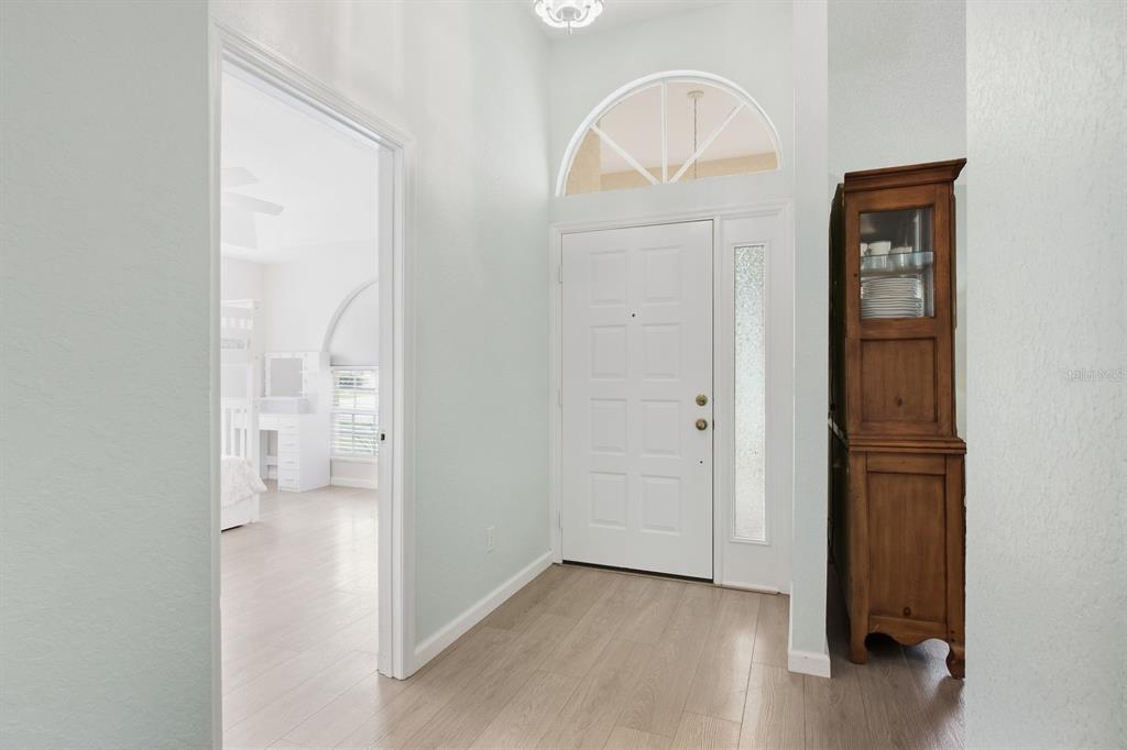 An entryway features a white front door with a sidelight, arched transom, and wood flooring — 5955 107TH TERRACE N, PINELLAS PARK, FL