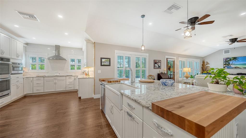 A bright kitchen features white cabinetry, granite countertops, a farmhouse sink, and hardwood flooring — 3606 PALONIA COURT, SARASOTA, FL