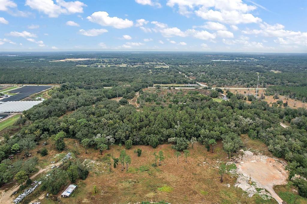 An aerial view shows a large, wooded plot of land with a cleared area and quarry — 34305 RIORDAN ROAD, EUSTIS, FL