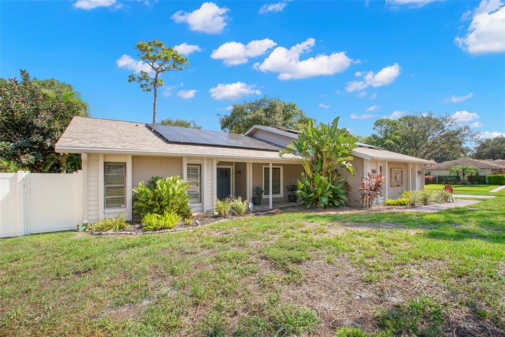 A single-story house with a tan exterior, solar panels on the roof, and a front yard — 1419 INDIAN TRAIL S, PALM HARBOR, FL