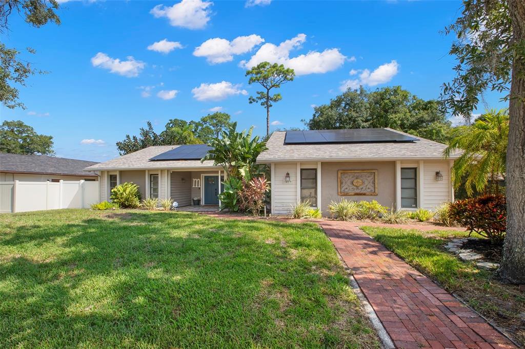 A single-story house with solar panels on the roof and a brick walkway leading inside — 1419 INDIAN TRAIL S, PALM HARBOR, FL