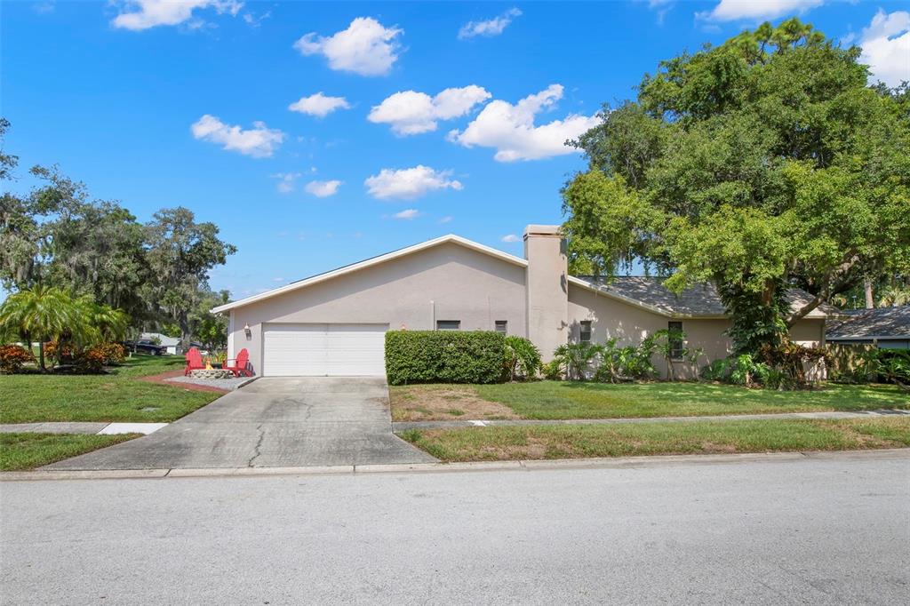 A single-story house with a white garage, a chimney, and a large tree in front — 1419 INDIAN TRAIL S, PALM HARBOR, FL