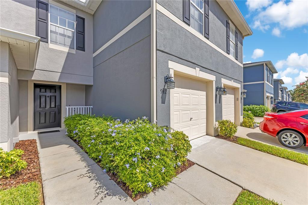 A two-story townhouse exterior features a front door, a garage, and a landscaped walkway — 942 COQUINA ROCK STREET, ORLANDO, FL