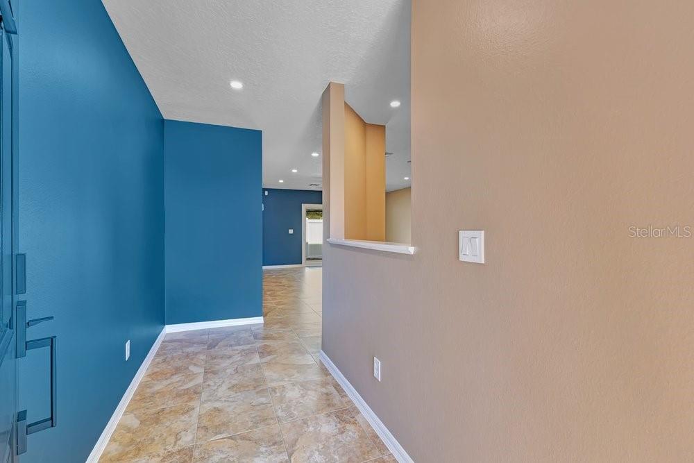 A row of three attached townhomes with gray stucco siding and beige garage doors — 942 COQUINA ROCK STREET, ORLANDO, FL