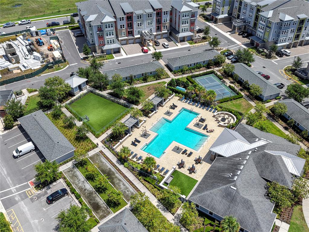 An aerial view shows a swimming pool, tennis court, and apartment buildings with parking lots — 7545 LAUREATE BOULEVARD UNIT 7408, ORLANDO, FL
