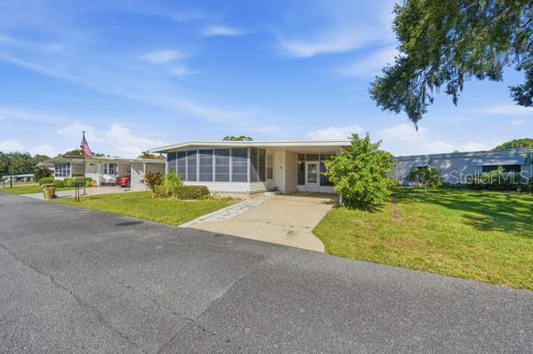 A single-story manufactured home with a screened-in porch and a concrete driveway — 101 MANGO COVE, LEESBURG, FL