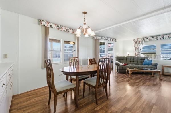A dining area with a wooden table and chairs sits next to a living room — 101 MANGO COVE, LEESBURG, FL