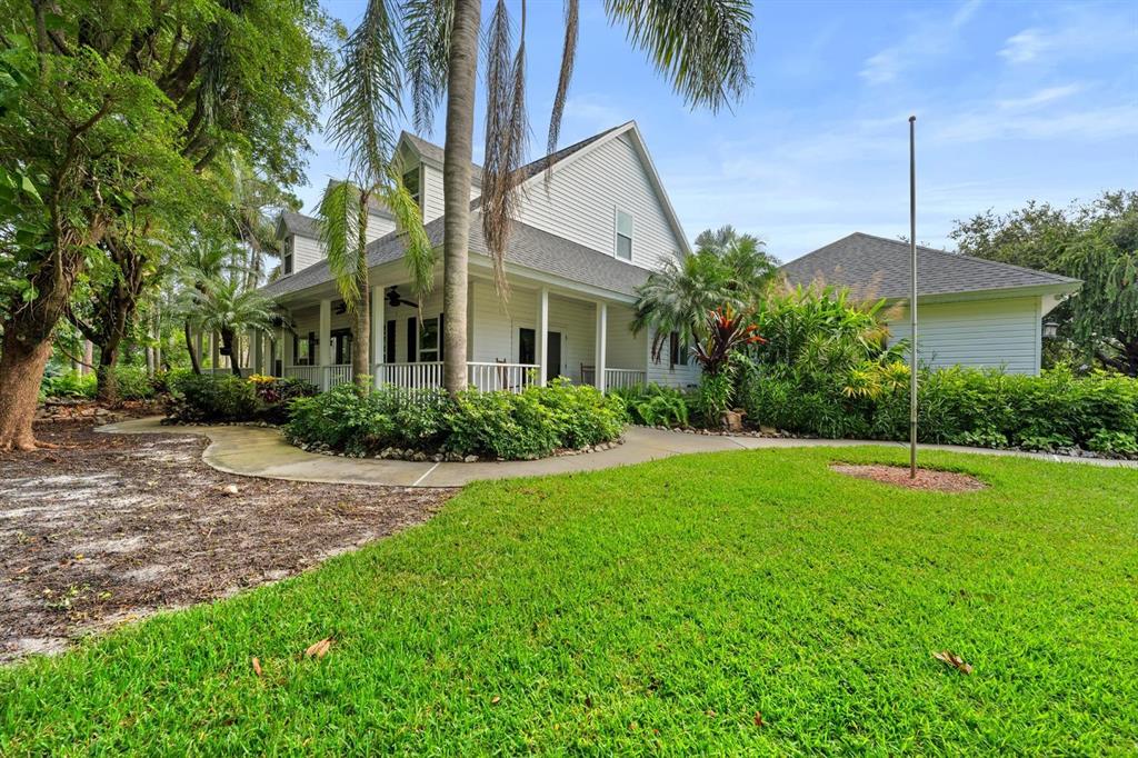 A two-story white house with a wrap-around porch and a detached garage — 6915 215TH STREET E, BRADENTON, FL
