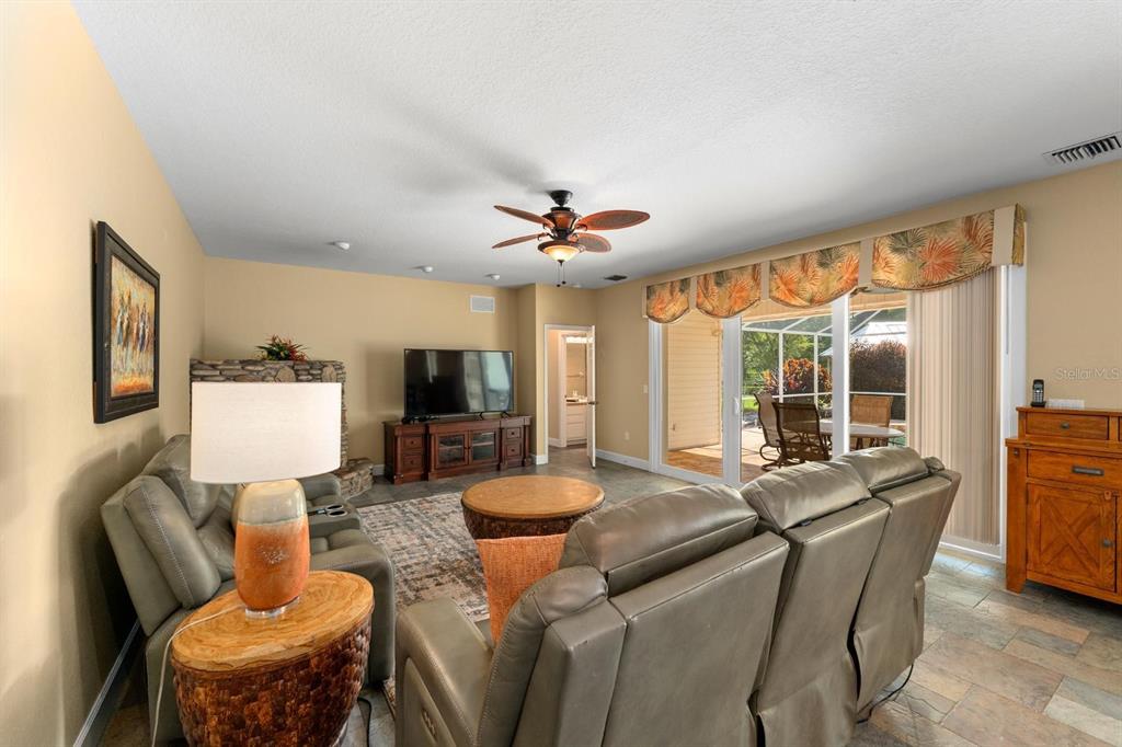 A living room with gray leather recliners, a stone fireplace, and sliding glass doors — 6915 215TH STREET E, BRADENTON, FL