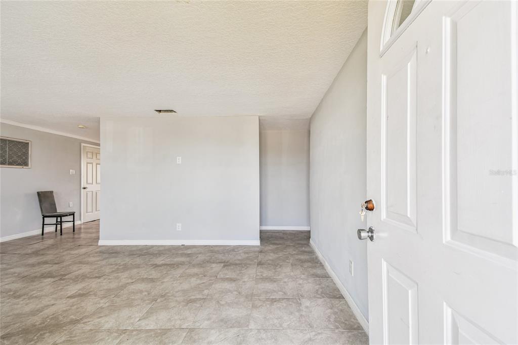 An interior view of a room with light gray walls, tile flooring, and an open doorway — 13606 ALLYN DRIVE, HUDSON, FL